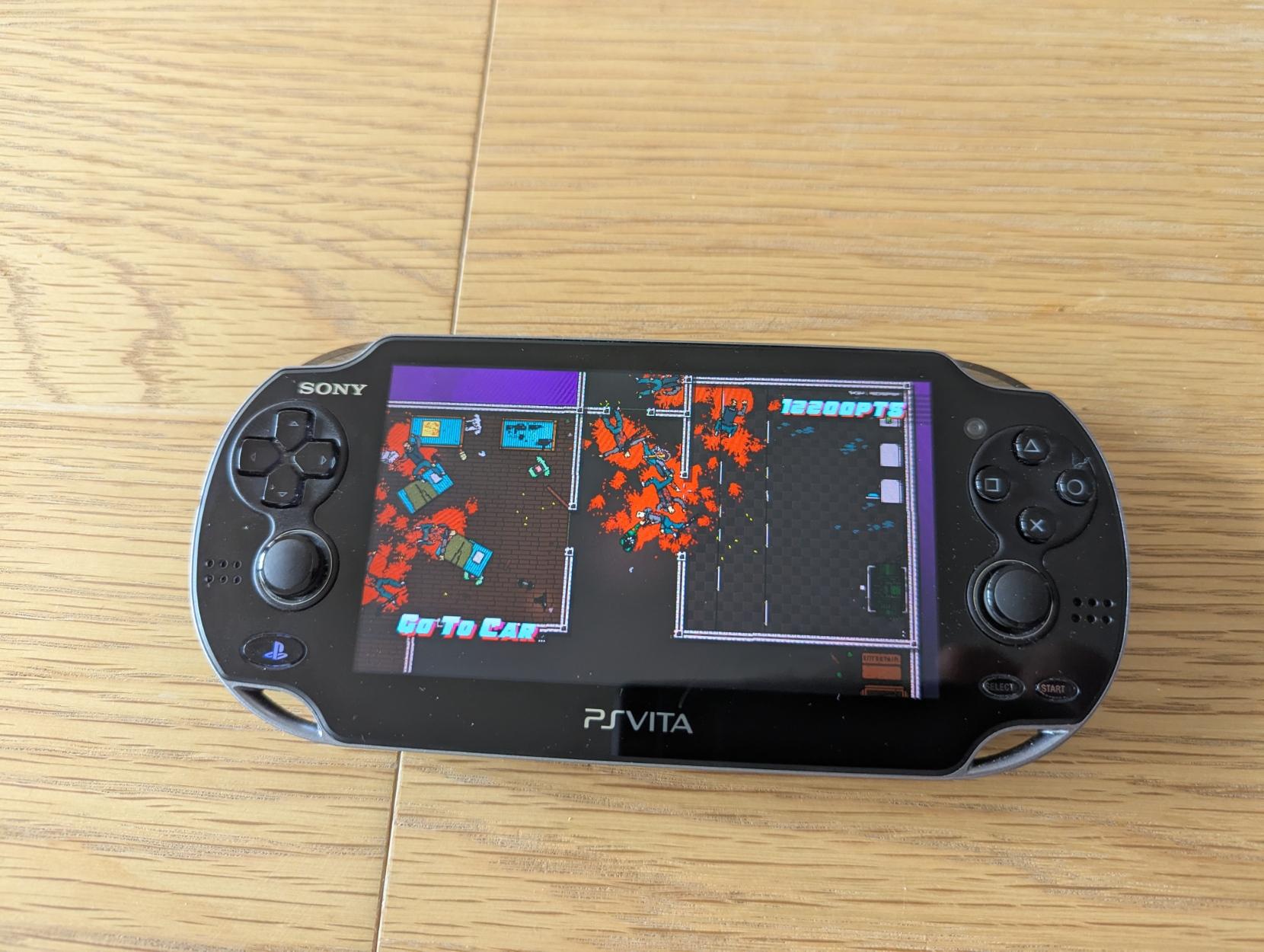 A PS Vita console displaying gameplay from Hotline Miami 2.